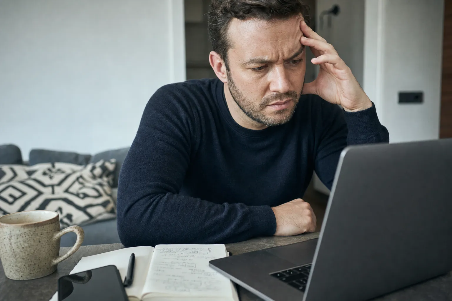 Someone reading a trading claim on a laptop, unconvinced, close on hands and notebook